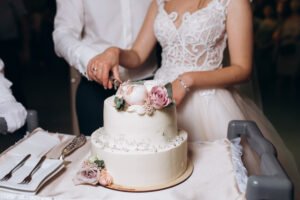 bride and groom are cutting decorated with flowers wedding cake